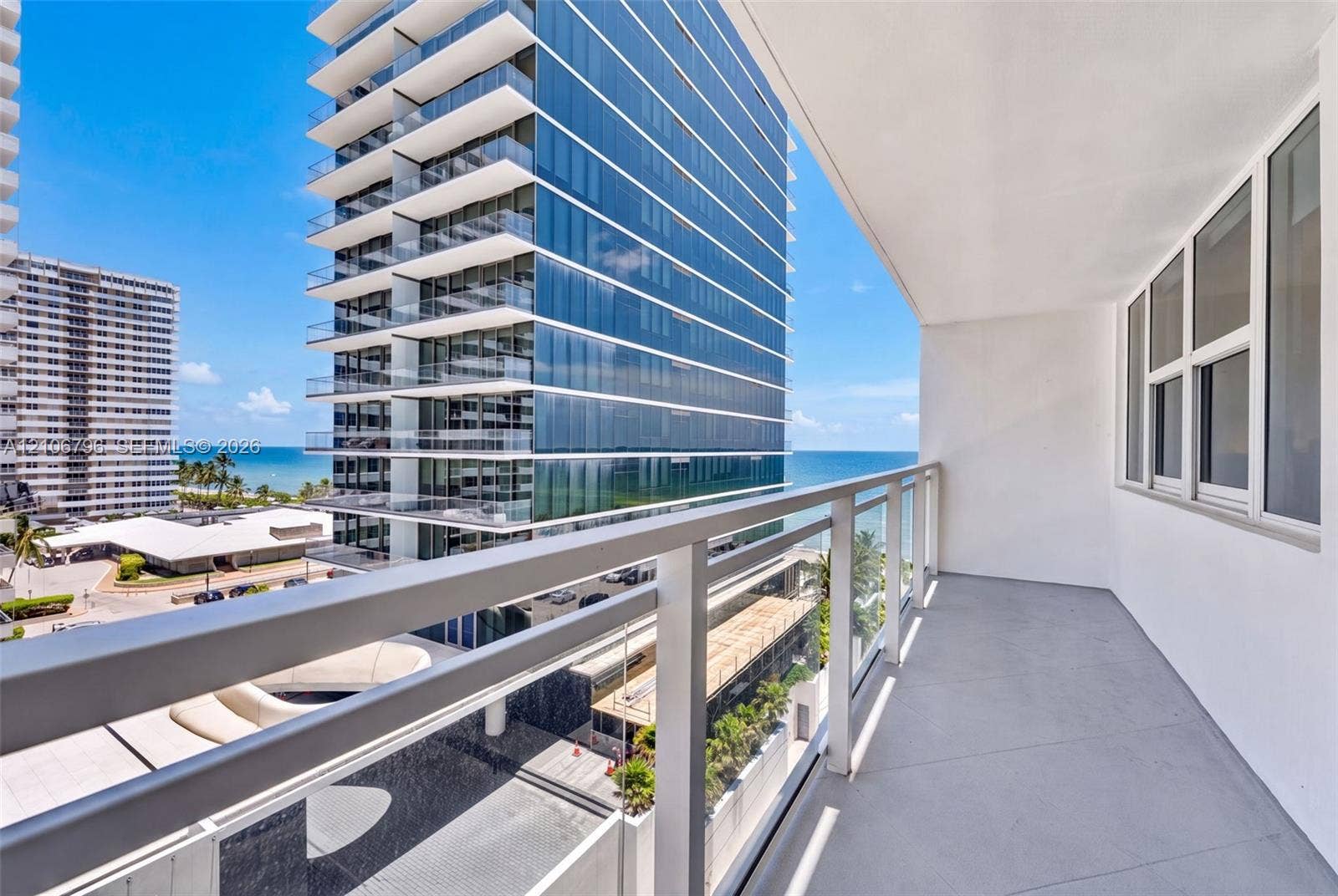 Private balcony featuring a glass-panel railing, concrete flooring, and large-format exterior windows