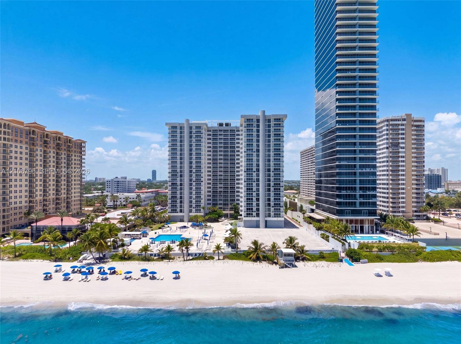 High-rise coastal towers featuring direct beach access, multiple outdoor swimming pools, expansive sun decks, and manicured palm landscaping
