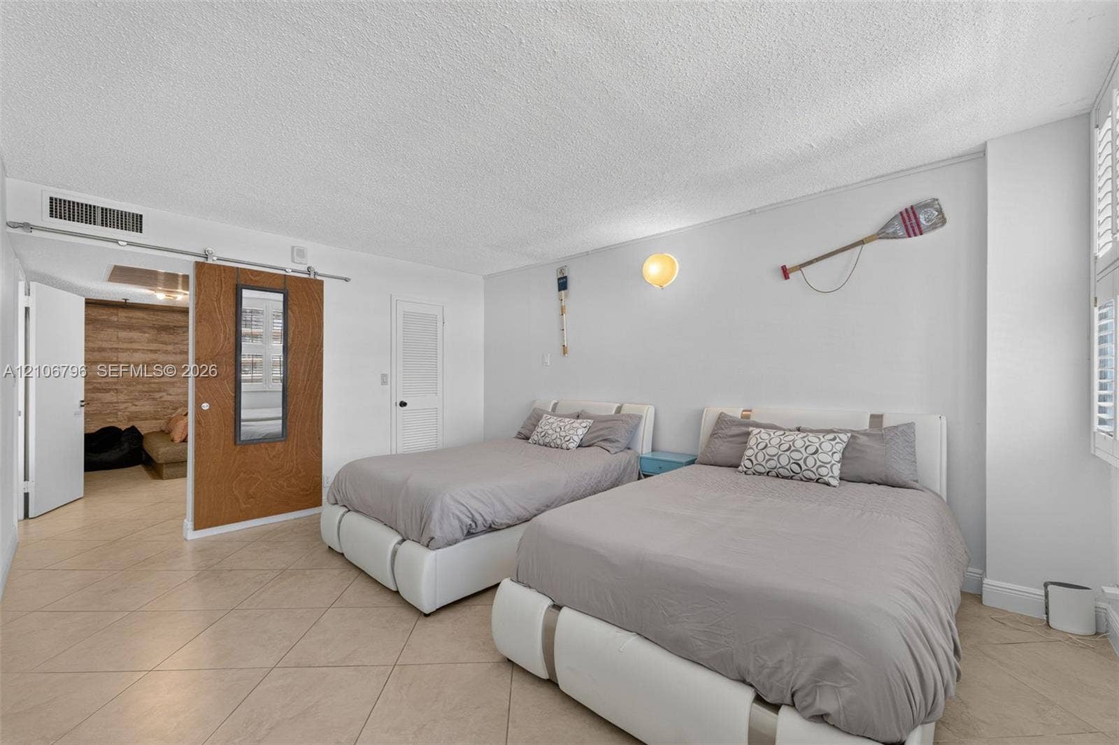 Ceramic tile flooring, sliding wood-finish barn door with inset mirror, and wall-mounted lighting fixture