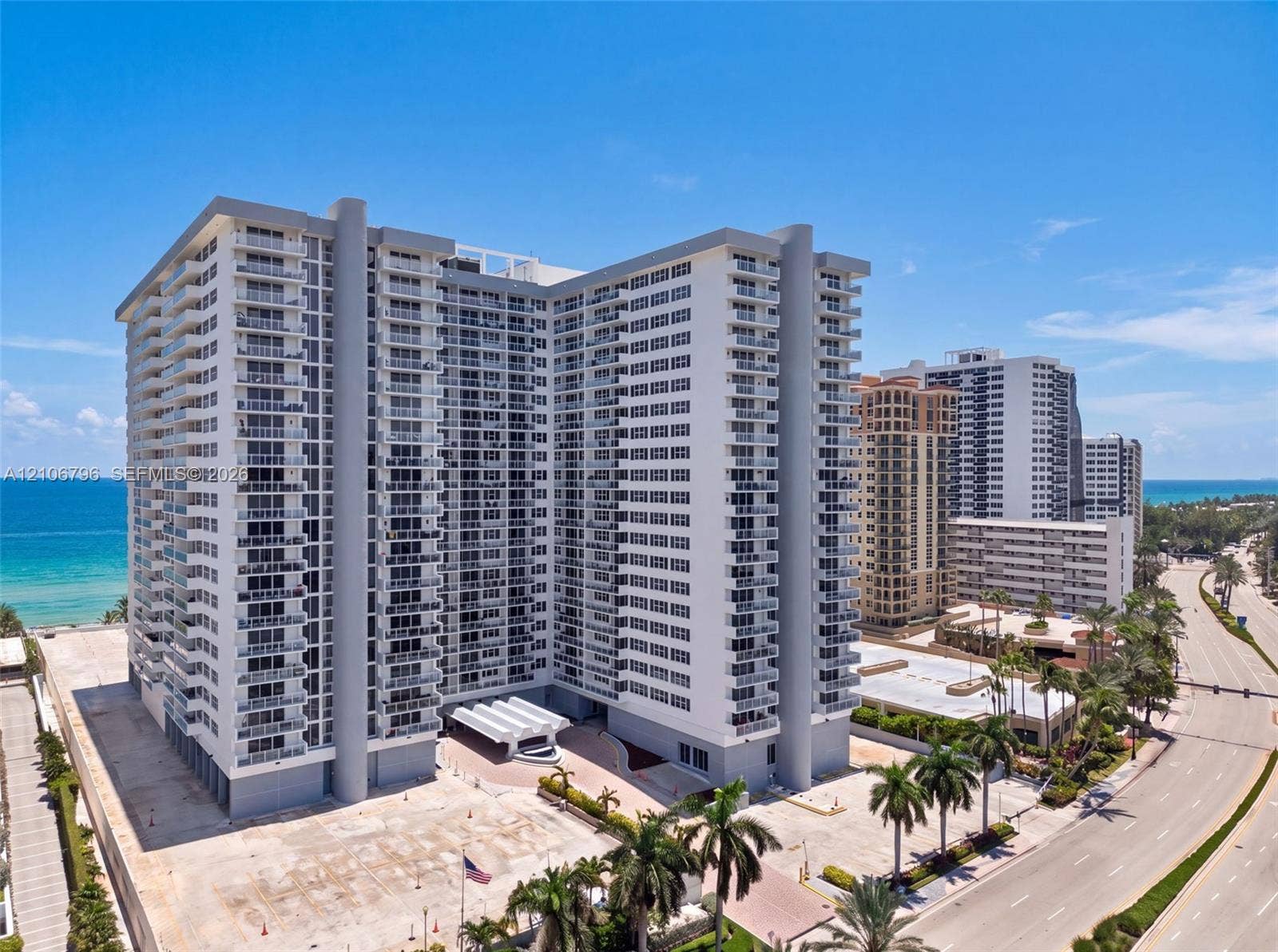 High-rise residential exterior featuring wrap-around balconies, a multi-tiered concrete facade, and a covered porte-cochre entrance