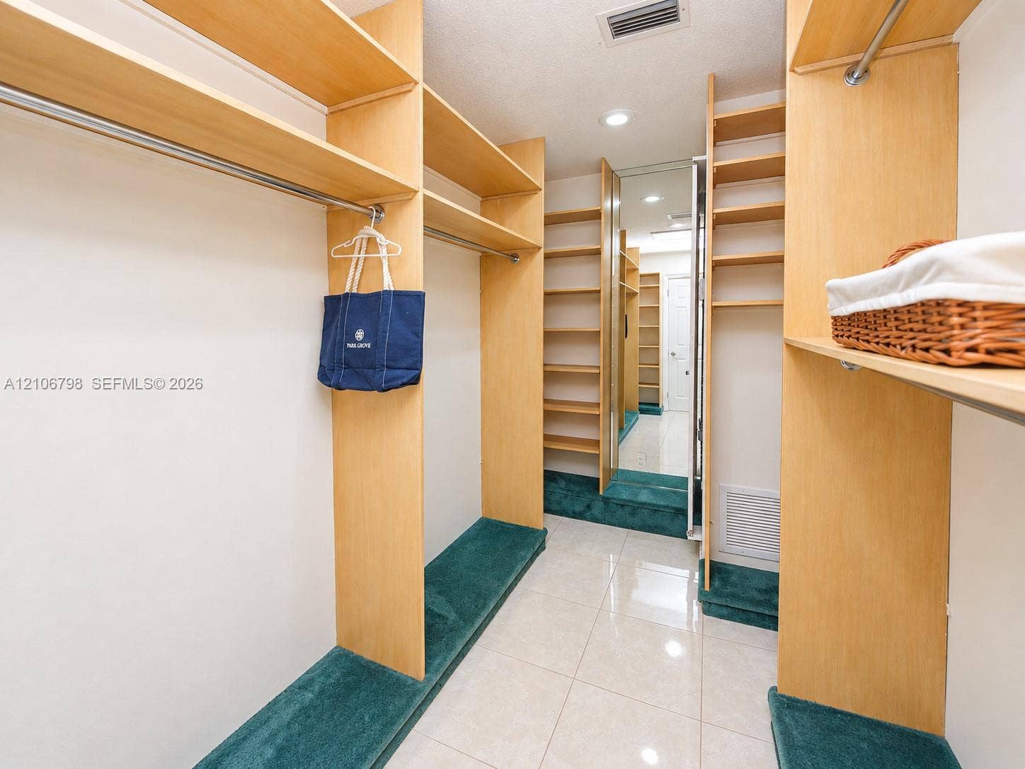 14750 SW 156th Street, Miami, FL 33187 Custom storage system with light wood-finish shelving and metal garment rods, full-length mirror paneling, and tile flooring