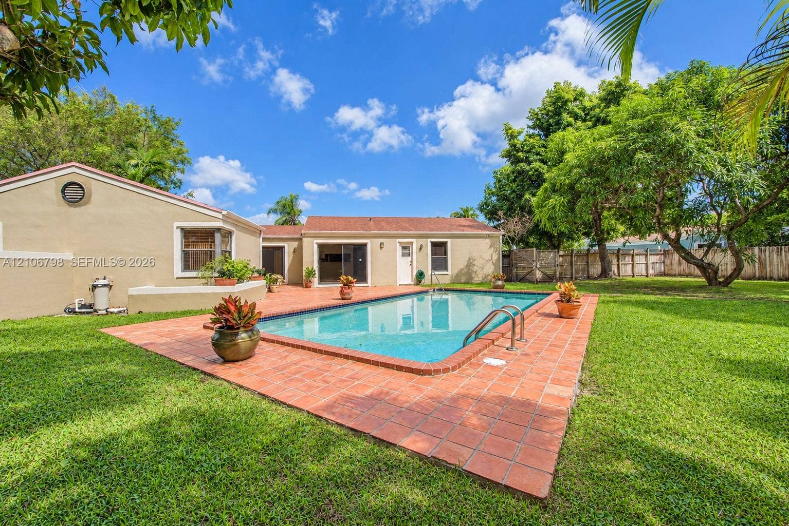 14750 SW 156th Street, Miami, FL 33187 Rear exterior featuring an in-ground swimming pool, tile patio surround, expansive lawn, and mature landscaping