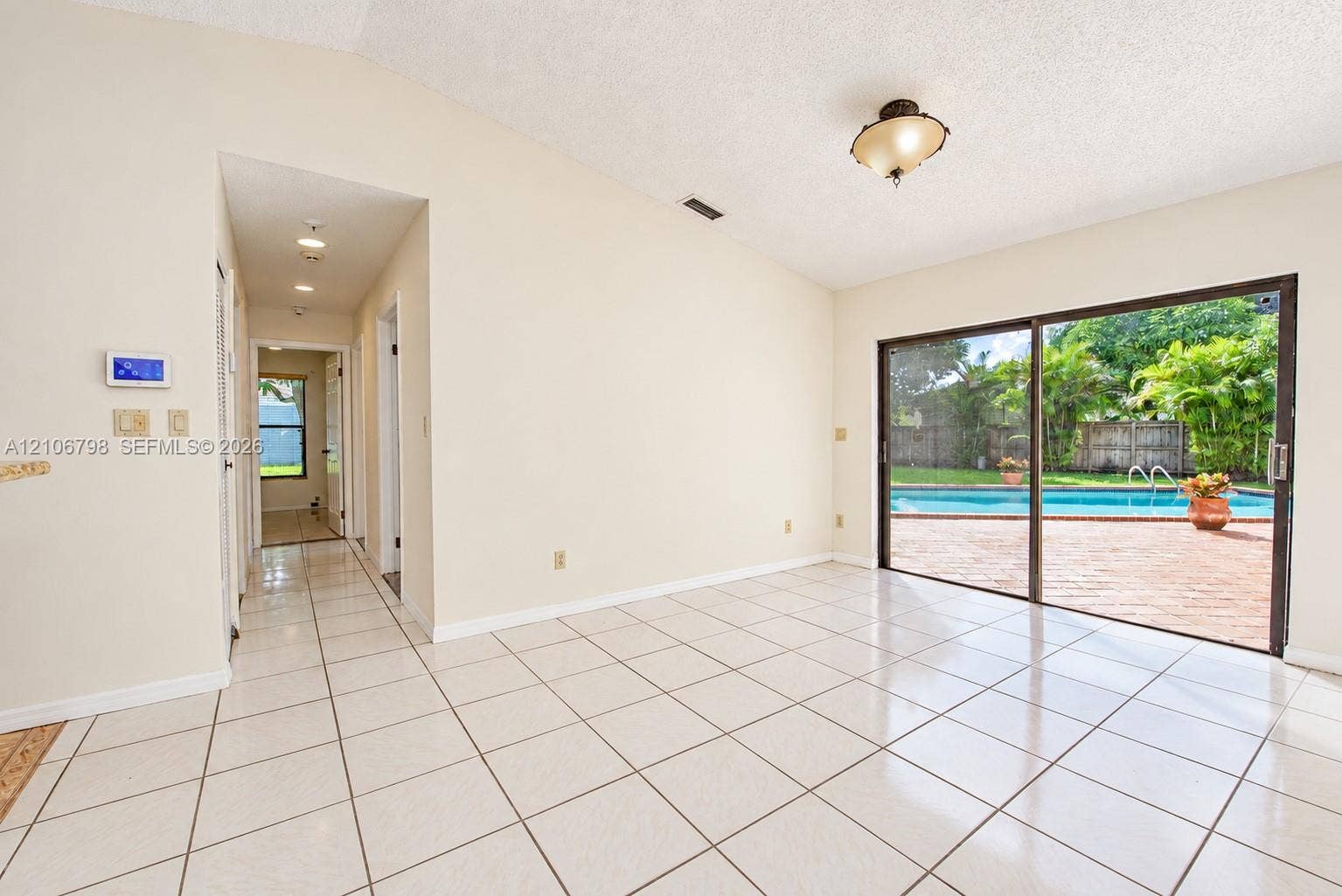 14750 SW 156th Street, Miami, FL 33187 Vaulted ceiling, ceramic tile flooring, sliding glass doors, and direct exterior access to a private swimming pool with a brick-paved deck