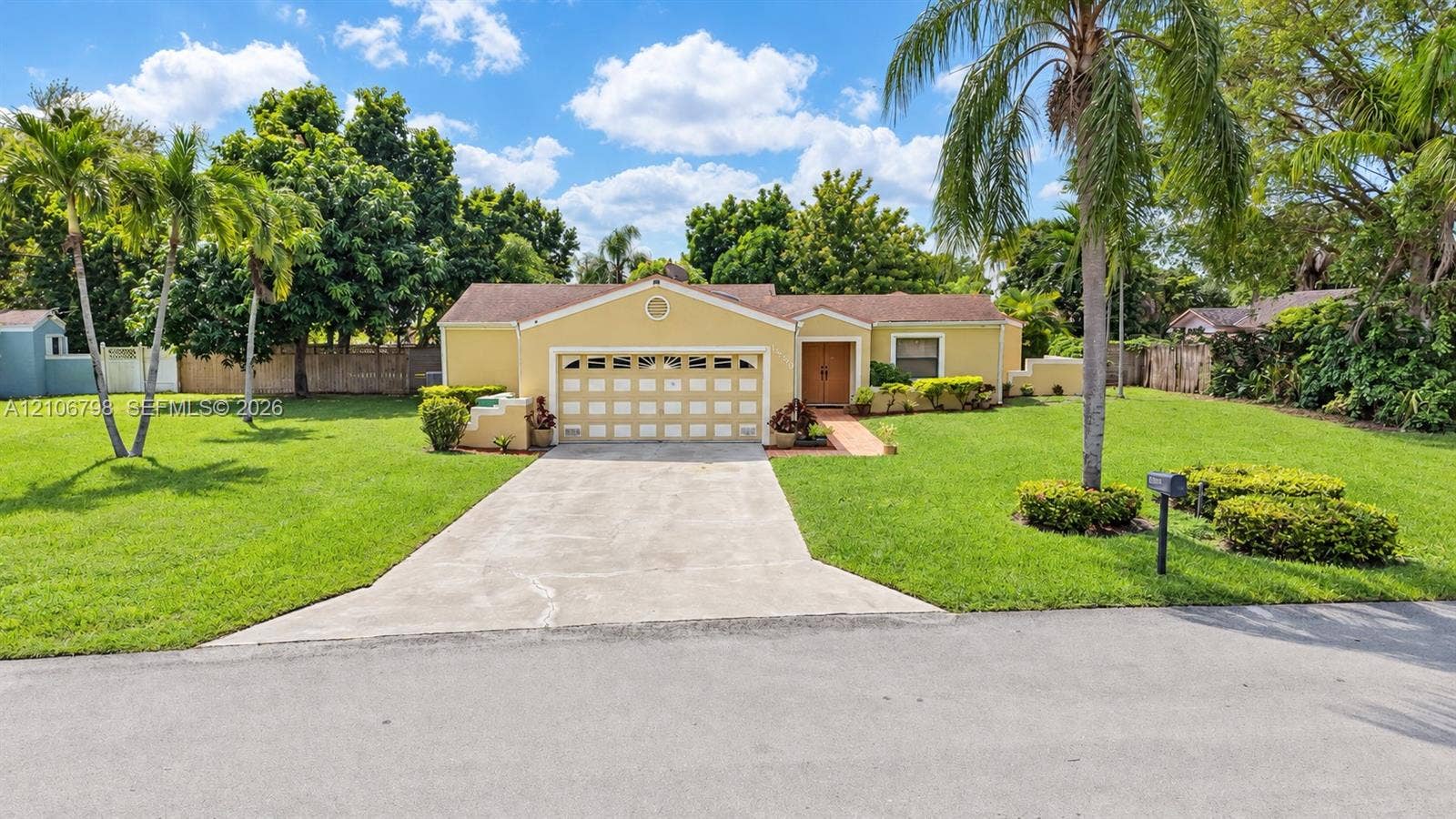 14750 SW 156th Street, Miami, FL 33187 Single-story residence featuring a multi-car garage, concrete driveway, and expansive front lawn with mature palm trees