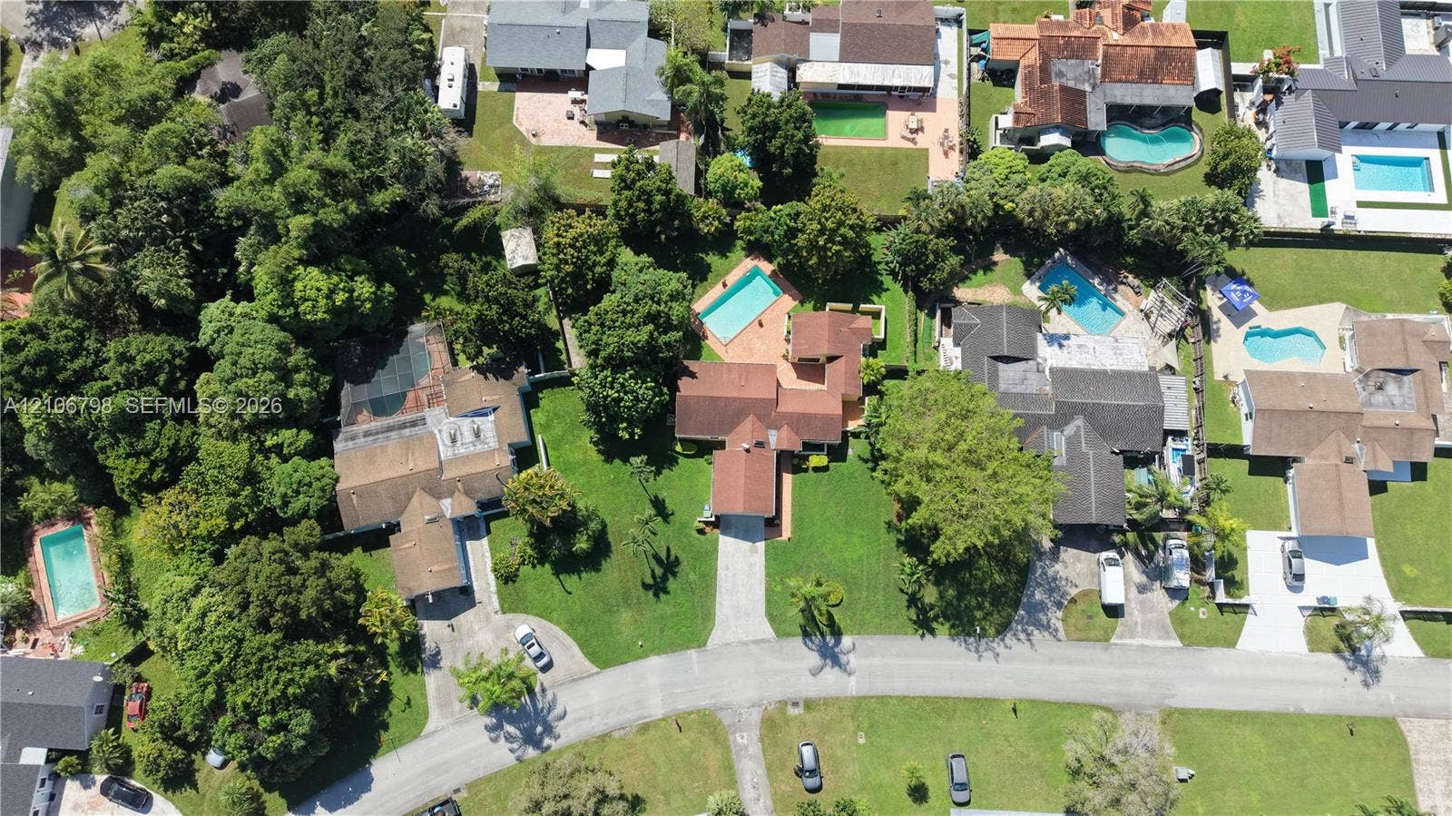 14750 SW 156th Street, Miami, FL 33187 Aerial perspective of a property featuring a private swimming pool, terracotta-tiled patio, paved driveway, expansive lawn, and mature trees