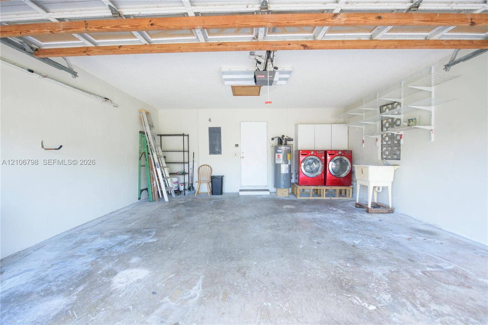 14750 SW 156th Street, Miami, FL 33187 Attached garage featuring a concrete floor, integrated wall shelving, built-in utility sink, and laundry hookups