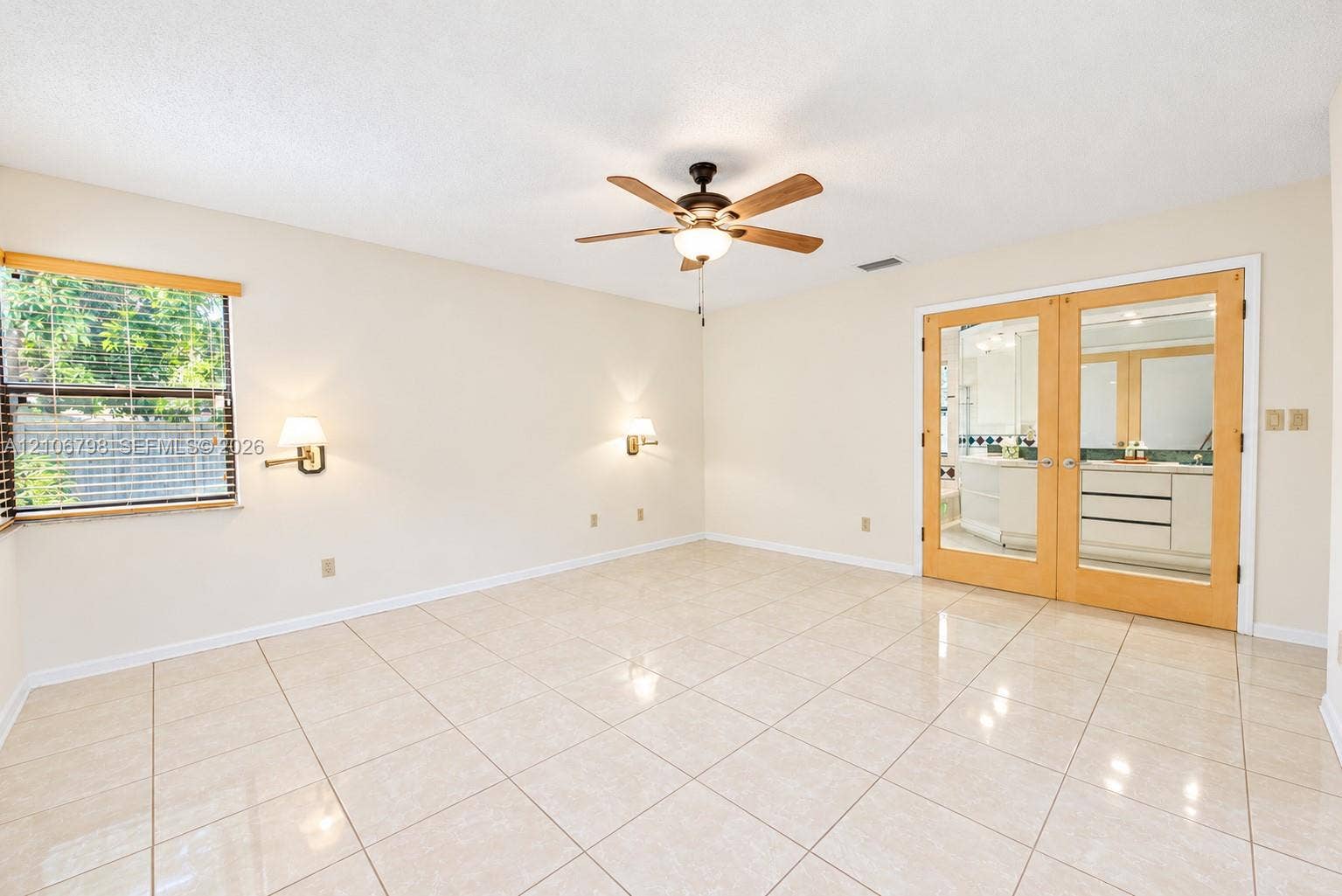 14750 SW 156th Street, Miami, FL 33187 Neutral tile flooring, ceiling fan with light fixture, twin wall-mounted sconces, and wood-framed glass-paneled double doors