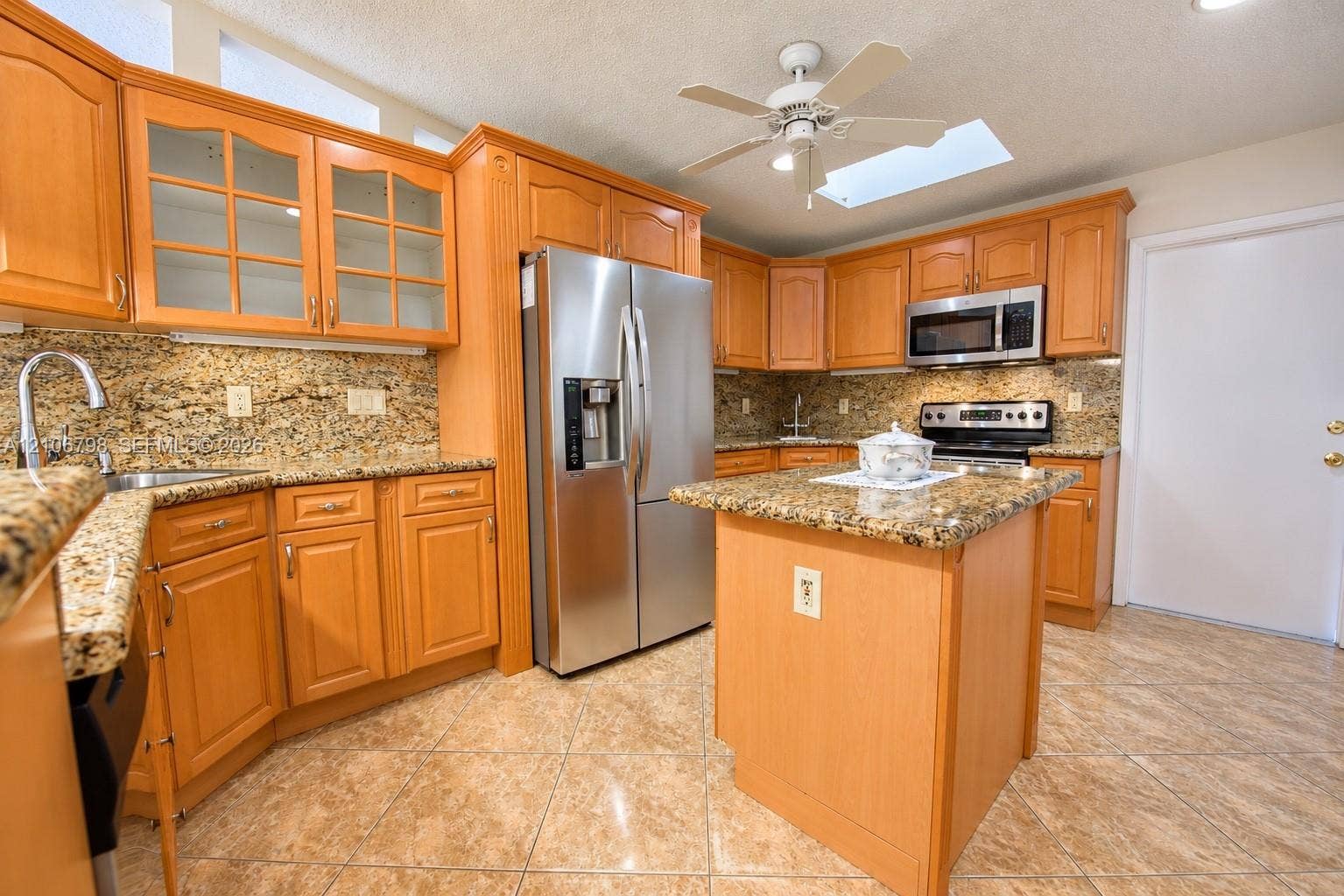 14750 SW 156th Street, Miami, FL 33187 Kitchen featuring natural wood cabinetry, stone countertops, stainless steel appliances, a center island, and a skylight