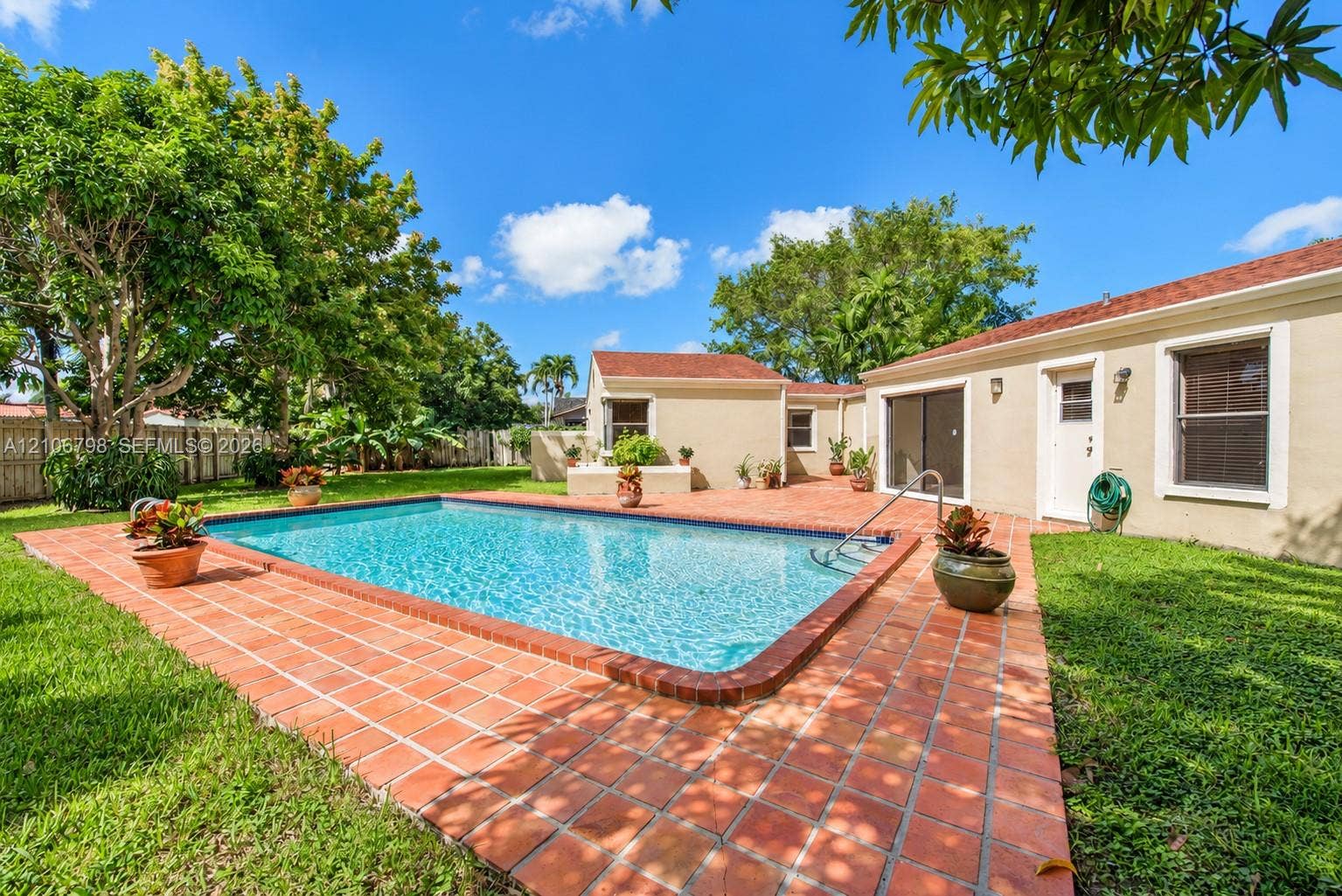 14750 SW 156th Street, Miami, FL 33187 Rectangular swimming pool surrounded by a terracotta tile deck, manicured lawn, and mature perimeter trees