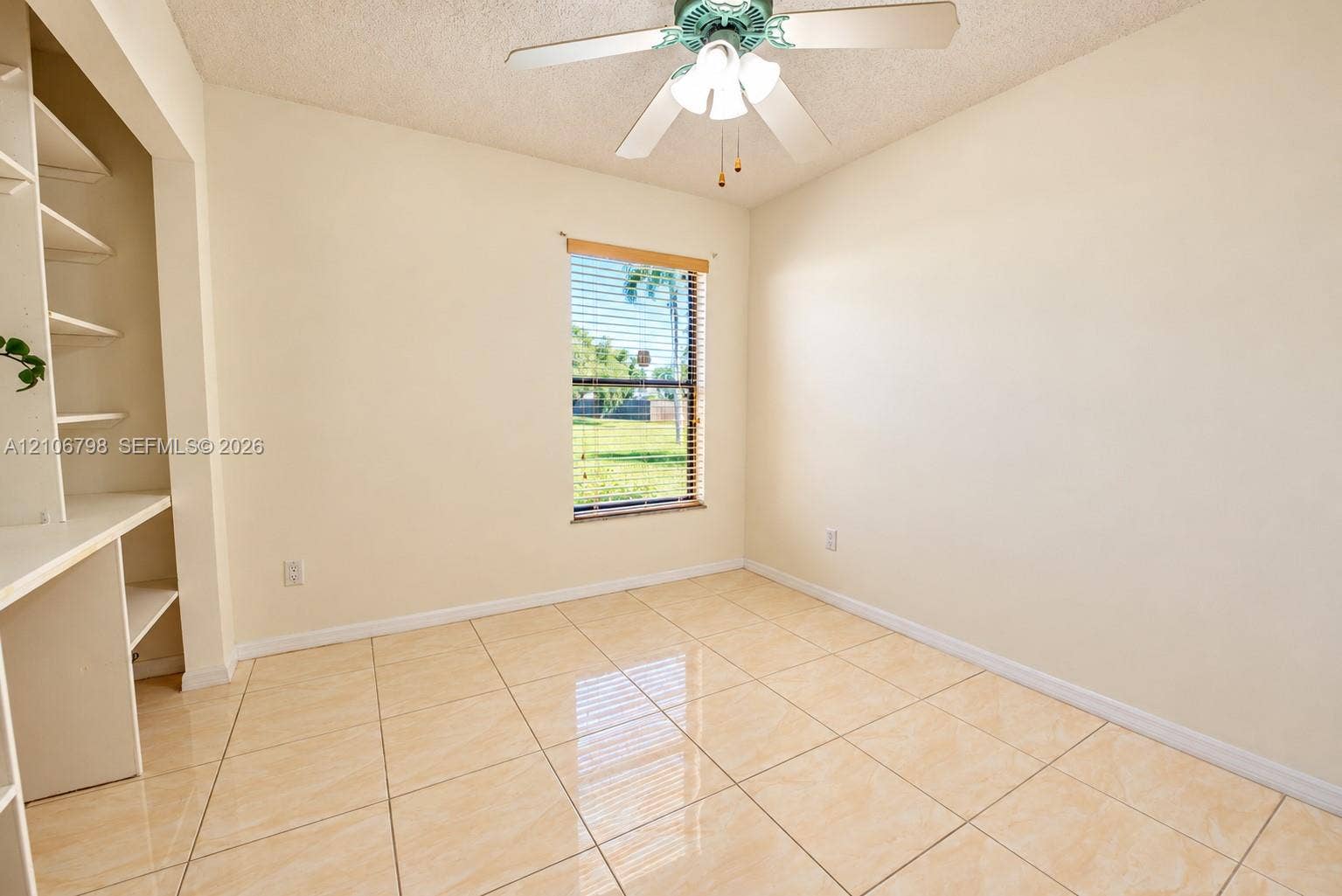 14750 SW 156th Street, Miami, FL 33187 Room featuring large-format ceramic tile flooring, built-in shelving with an integrated desk, and a ceiling fan with integrated lighting