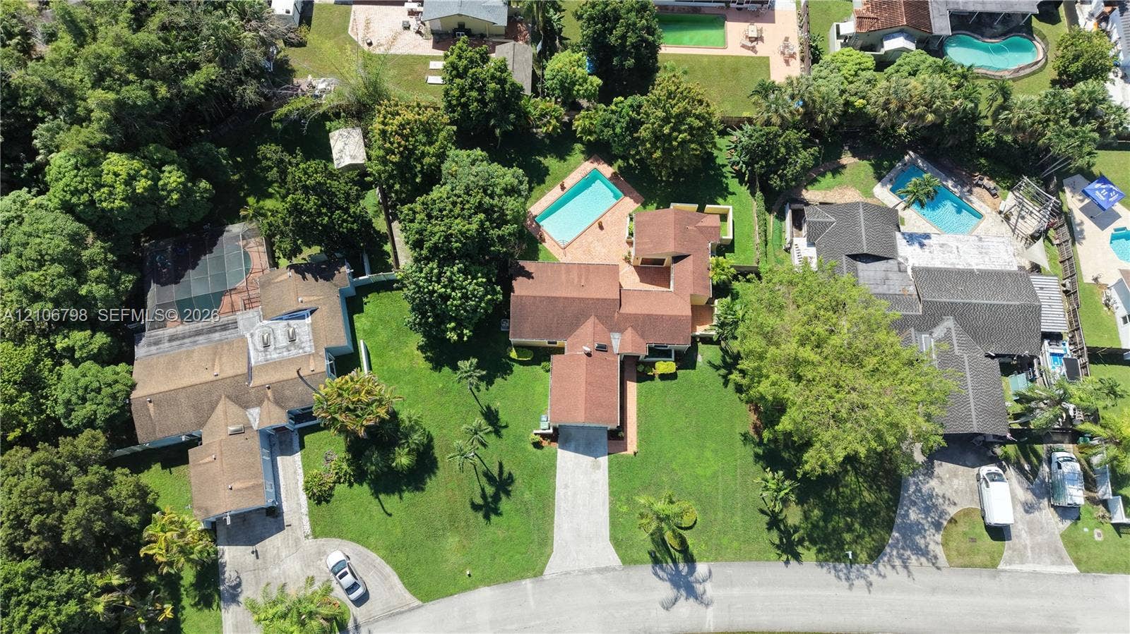 14750 SW 156th Street, Miami, FL 33187 Aerial perspective of residential property featuring a multi-pitched roofline, a backyard swimming pool, paved driveway, and mature landscaping