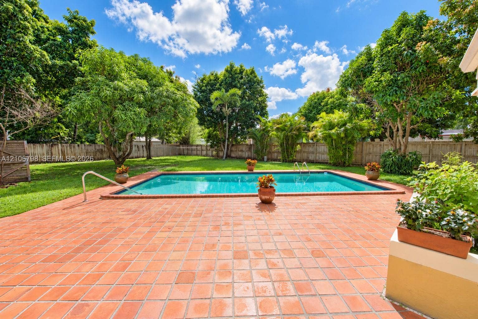 14750 SW 156th Street, Miami, FL 33187 Rectangular in-ground swimming pool with metal handrails, expansive brick patio, fenced perimeter, and mature landscaping