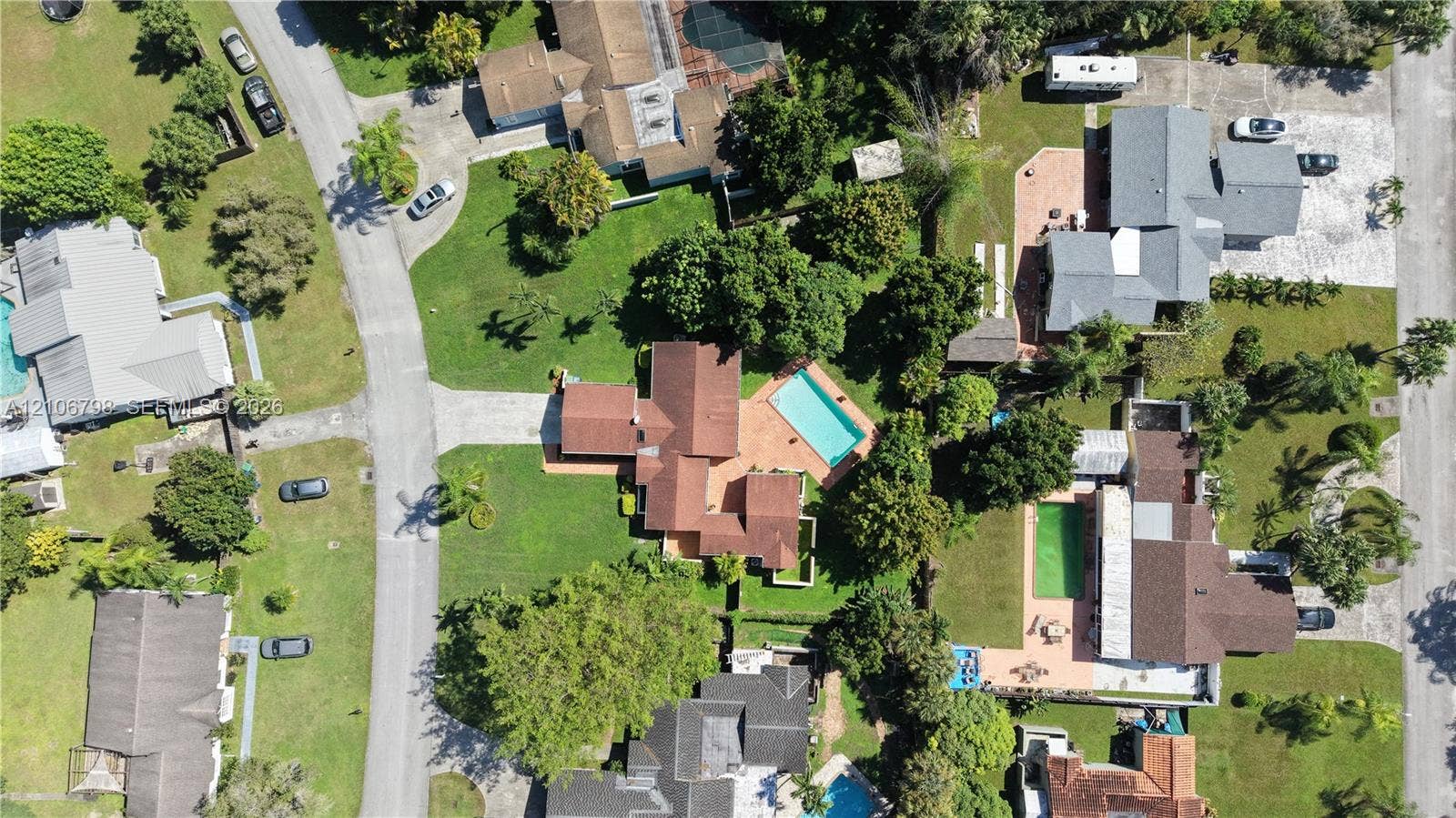 14750 SW 156th Street, Miami, FL 33187 Aerial perspective featuring a multi-gabled roofline, concrete driveway, swimming pool, and established landscape