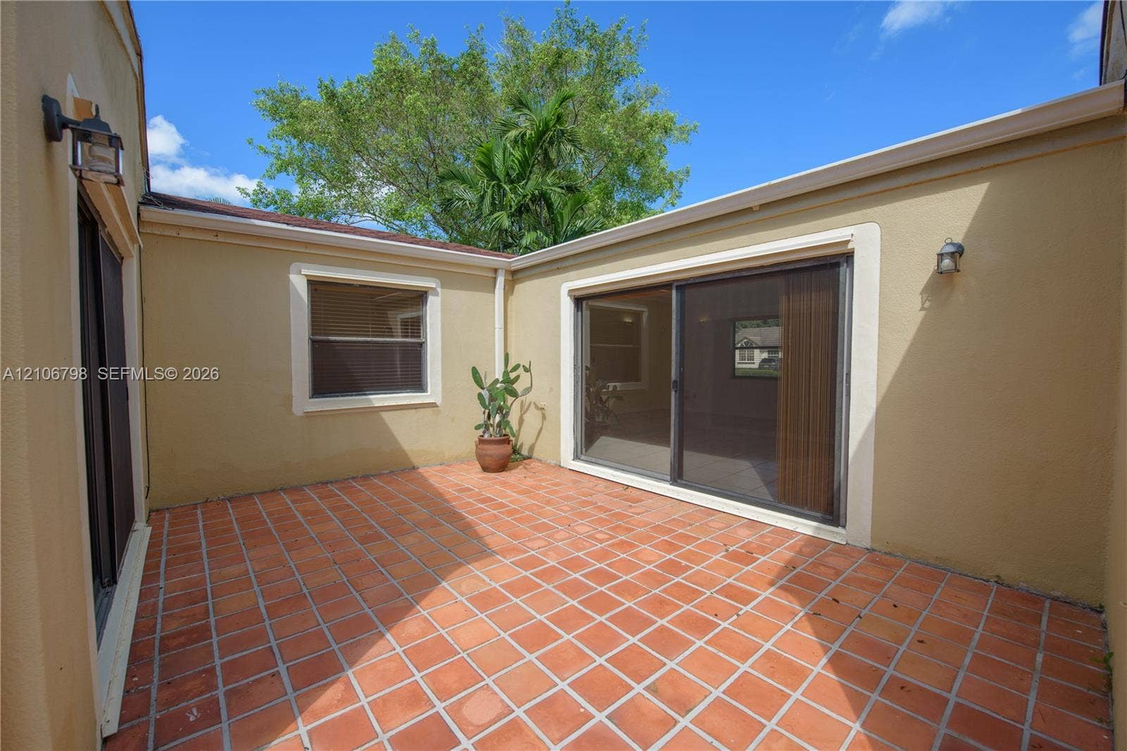 14750 SW 156th Street, Miami, FL 33187 Private courtyard featuring terra-cotta tile flooring, stucco exterior walls, and two sets of sliding glass doors