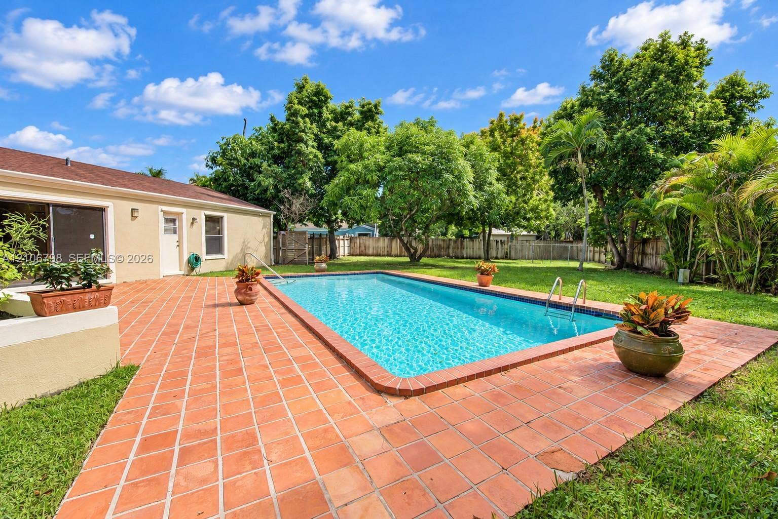 14750 SW 156th Street, Miami, FL 33187 Private backyard featuring an in-ground swimming pool, terracotta tile patio, expansive lawn, mature trees, and perimeter fencing