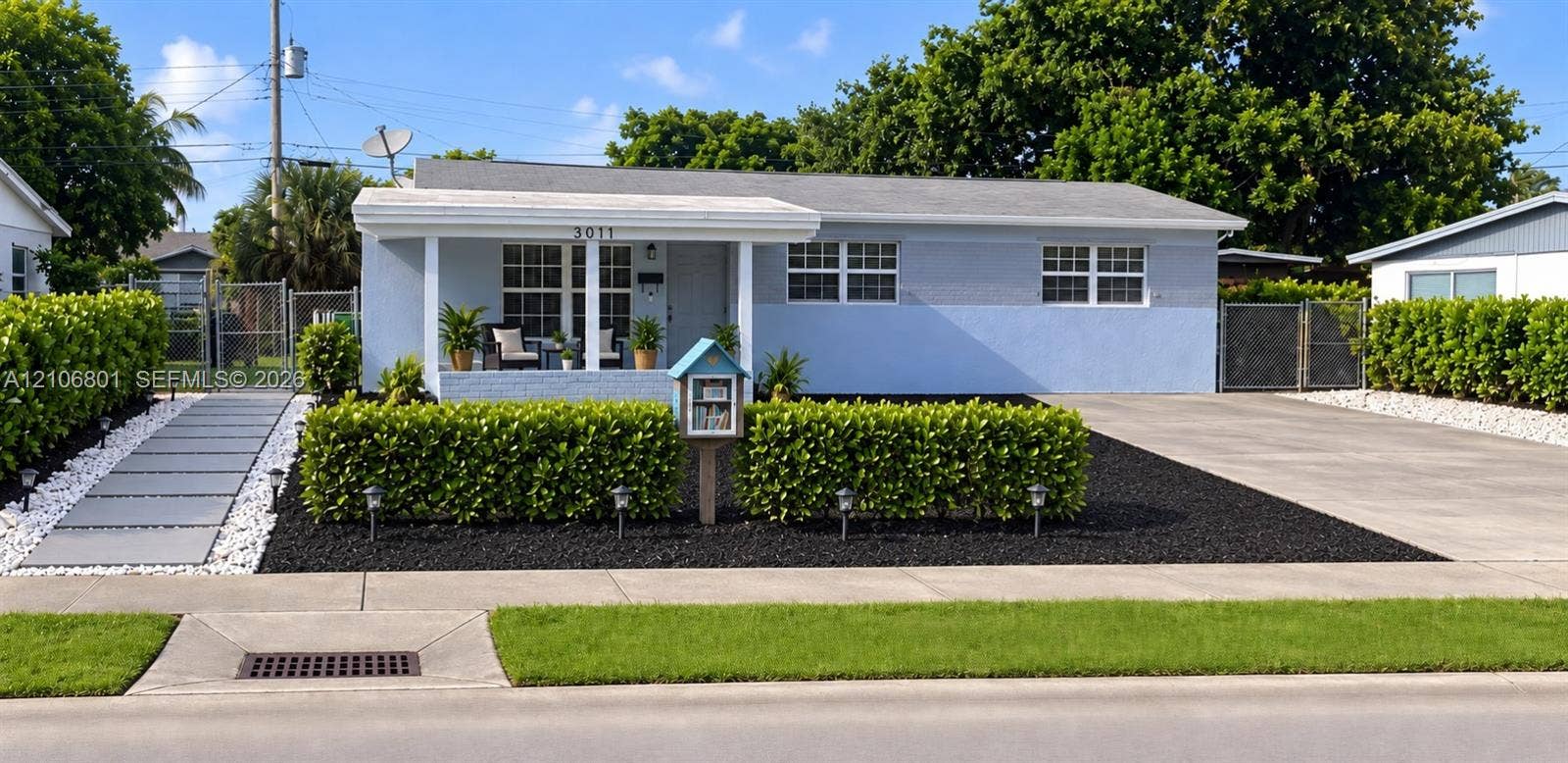 Single-story exterior featuring a covered front porch, concrete driveway, stone-accented front walkway, and manicured shrubbery