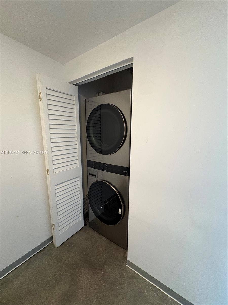 690 SW 1st Court, #1212, Miami, FL 33130 Stacked stainless steel laundry center enclosed by a white louvered door
