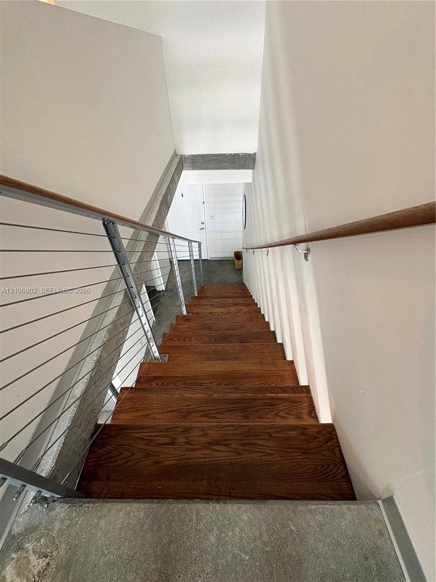 690 SW 1st Court, #1212, Miami, FL 33130 Staircase featuring wood treads, stainless steel cable railing, and a wall-mounted wooden handrail