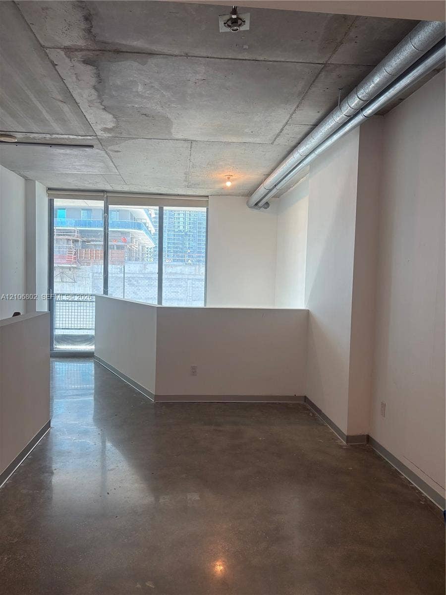 690 SW 1st Court, #1212, Miami, FL 33130 Industrial-style interior featuring exposed concrete ceilings, polished concrete flooring, floor-to-ceiling windows, and exposed metallic ductwork