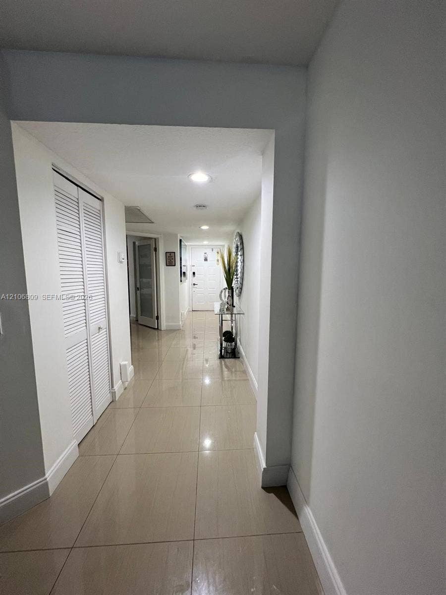 12600 SW 5th Court, #204L, Pembroke Pines, FL 33027 Hallway featuring large-format tile flooring, recessed ceiling lighting, and louvered double-door closet cabinetry