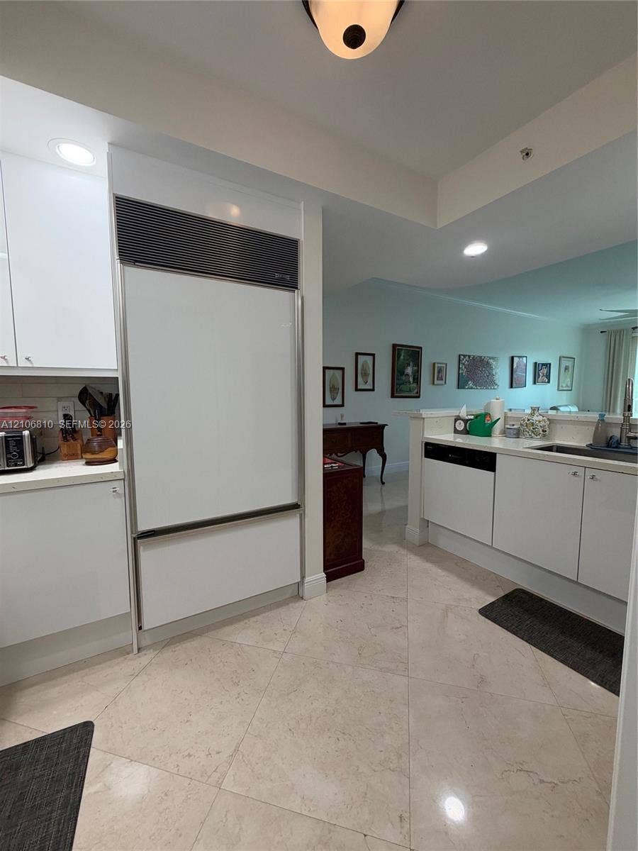 Kitchen featuring white cabinetry, panel-ready refrigerator, recessed lighting, stone-finish flooring, and solid-surface countertops
