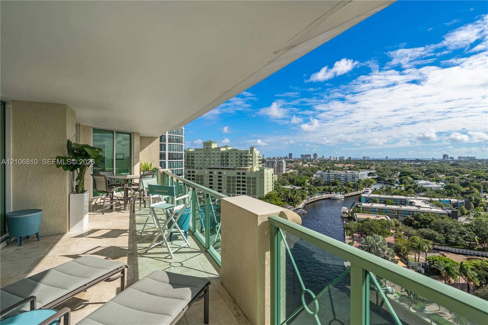 Covered balcony featuring stone flooring and metal railings, overlooking a waterway and urban skyline