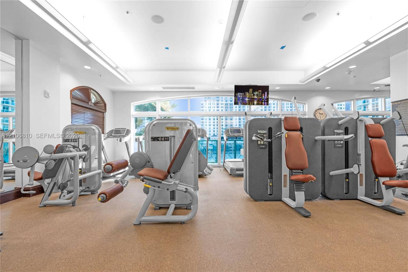 Fitness center featuring high ceilings, recessed lighting, expansive windows, wall-to-wall rubber flooring, and built-in ceiling speakers