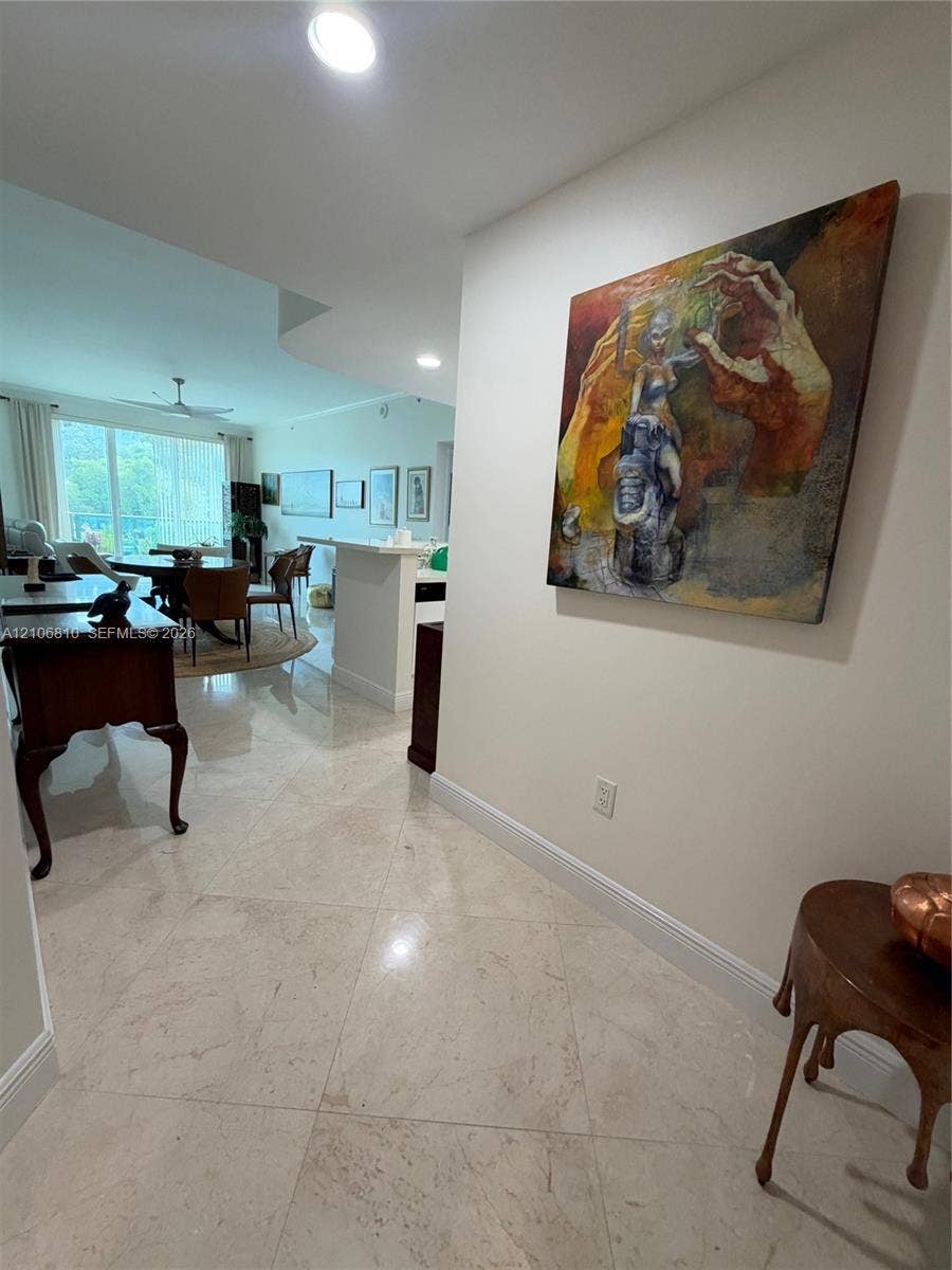 Polished stone tile flooring, recessed ceiling lighting, and a breakfast bar