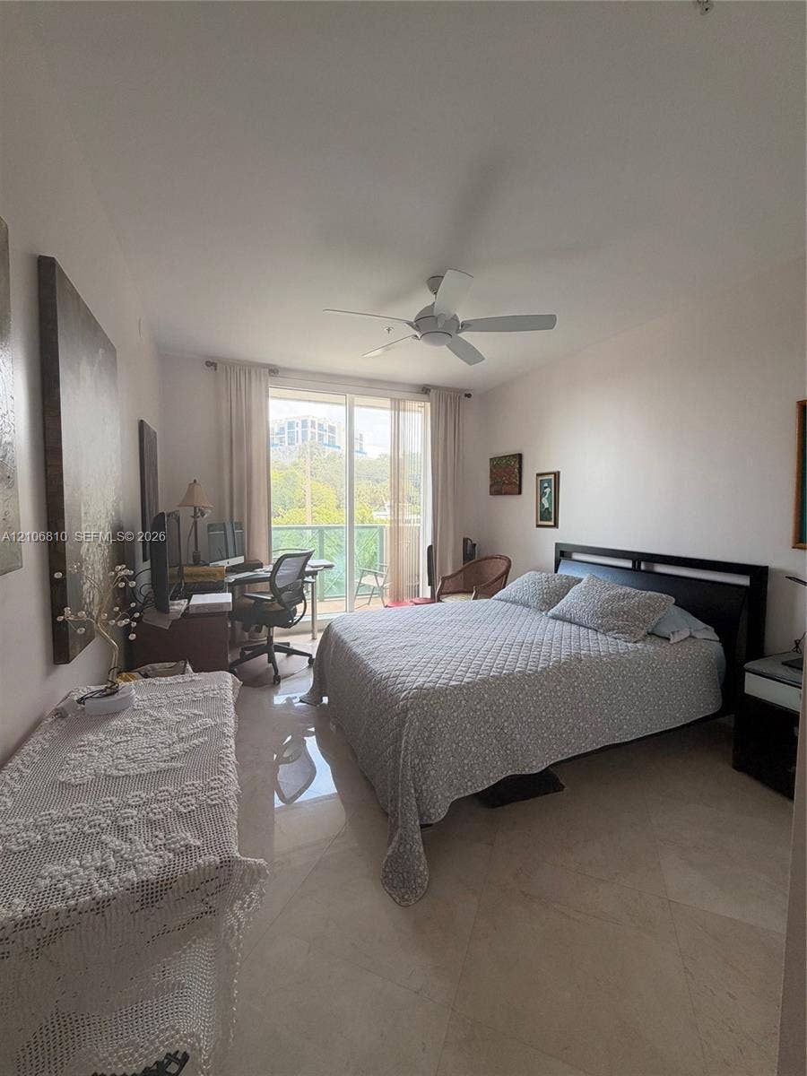 Room featuring light-toned tile flooring, ceiling fan with integrated lighting, and glass sliding doors providing exterior balcony access