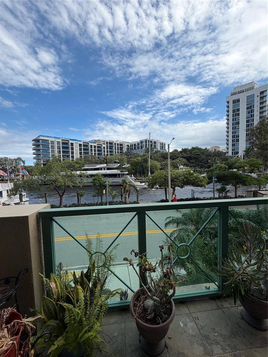 Balcony featuring green metal railing, tiled flooring, and exterior water scenery