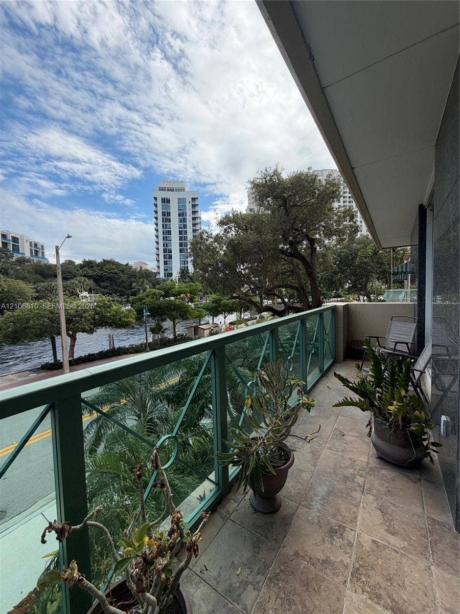 Covered balcony featuring stone-tile flooring and a decorative metal railing