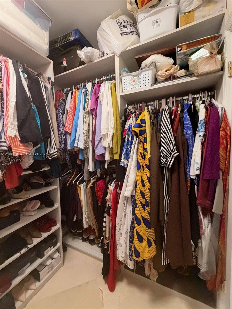 Customized walk-in closet featuring floor-to-ceiling built-in cabinetry, tiered shelving for shoe storage, and dual-level metal hanging rods