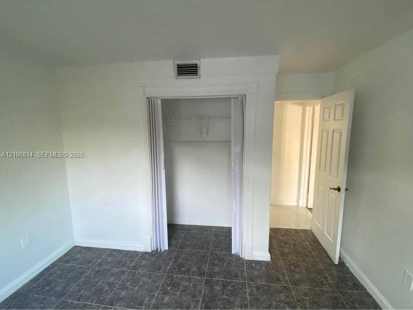 6503 Winfield Boulevard, #211AD, Margate, Margate, FL 33063 Room interior featuring large-format tile flooring, a closet with bi-fold doors and built-in shelving, and a traditional six-panel door