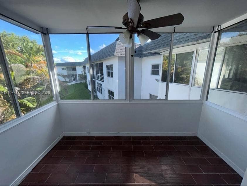 6503 Winfield Boulevard, #211AD, Margate, Margate, FL 33063 Enclosed sunroom featuring expansive windows, red-toned tile flooring, and a ceiling-mounted light fixture with a fan