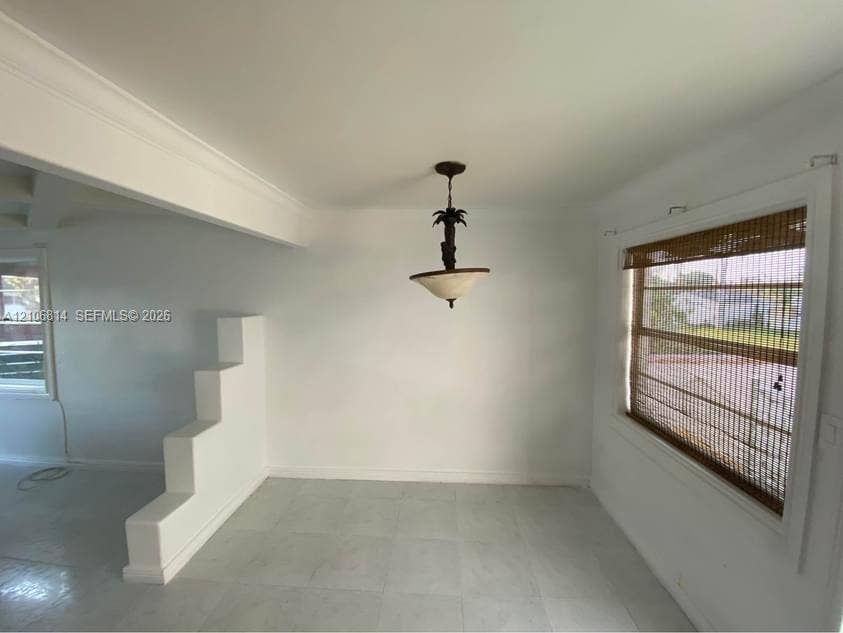 6503 Winfield Boulevard, #211AD, Margate, Margate, FL 33063 Interior space featuring a stepped architectural partition, neutral tile flooring, and a decorative pendant light fixture with a translucent shade