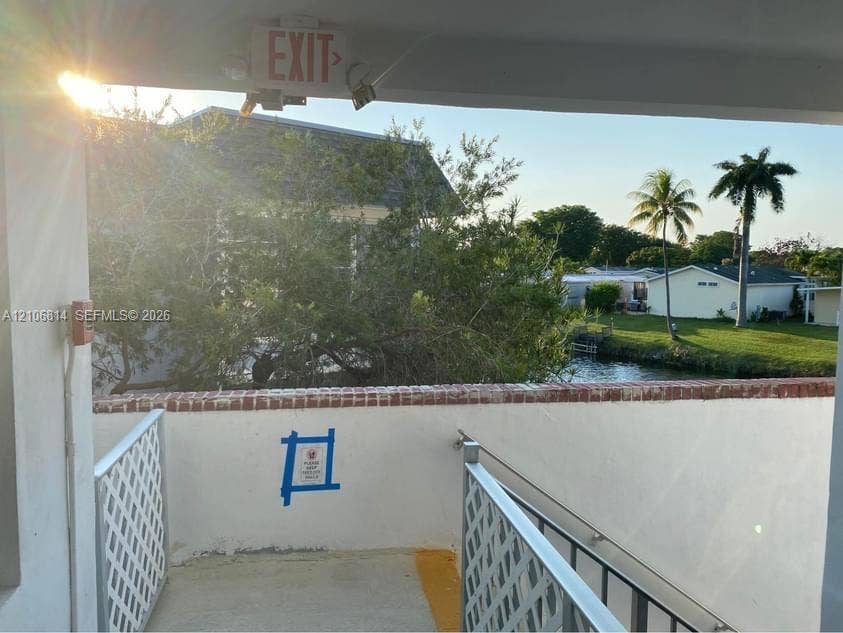 6503 Winfield Boulevard, #211AD, Margate, Margate, FL 33063 Outdoor landing featuring a masonry half-wall with a brick cap, white lattice railing, and a metal handrail