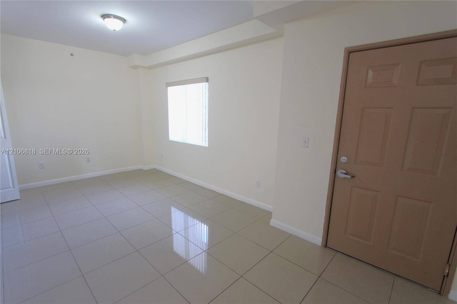 Neutral-toned ceramic tile flooring, solid-core interior door, and a flush-mount ceiling light fixture