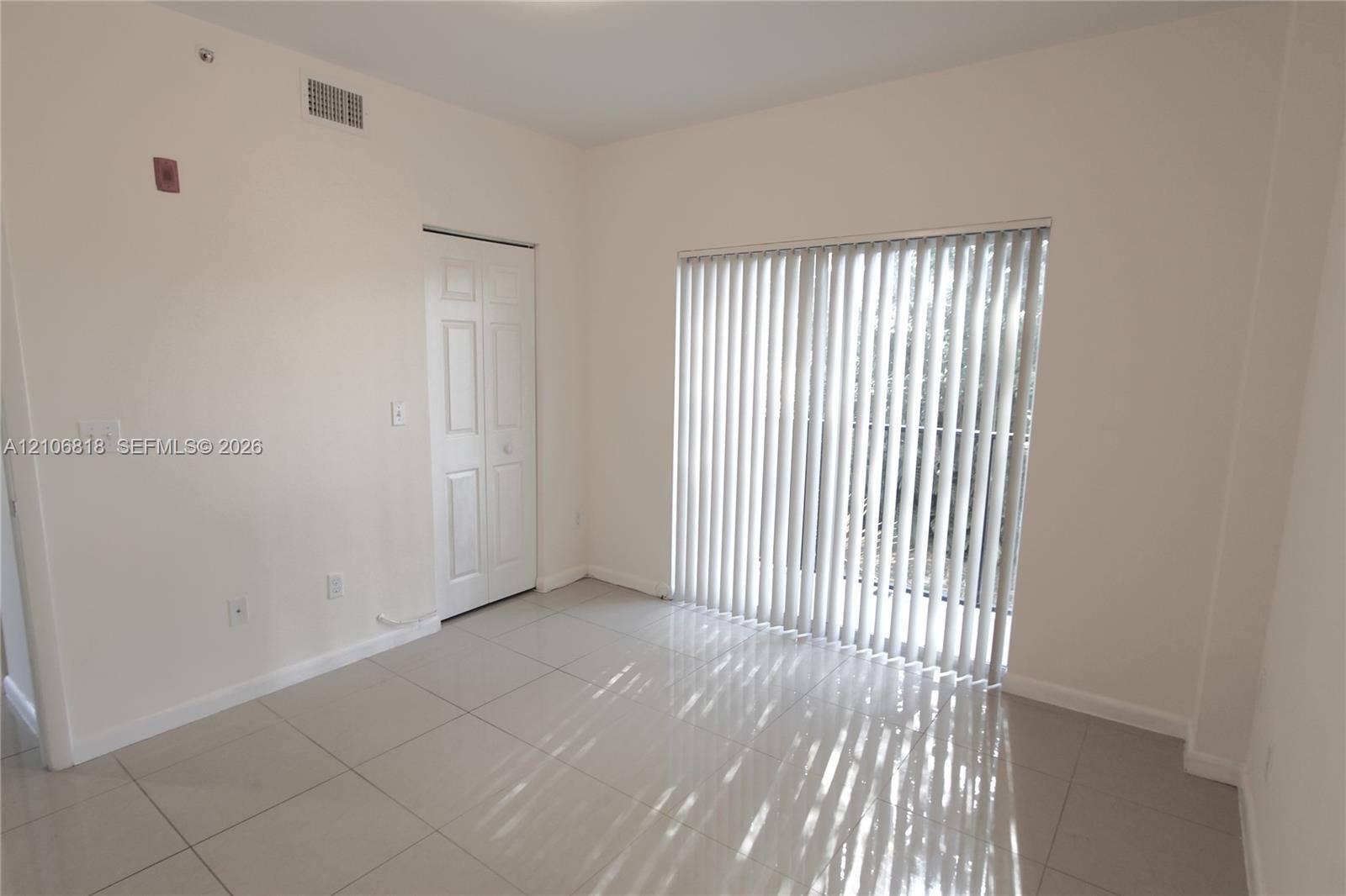 Interior space featuring large-format ceramic tile flooring, vertical window blinds, and a bi-fold closet door