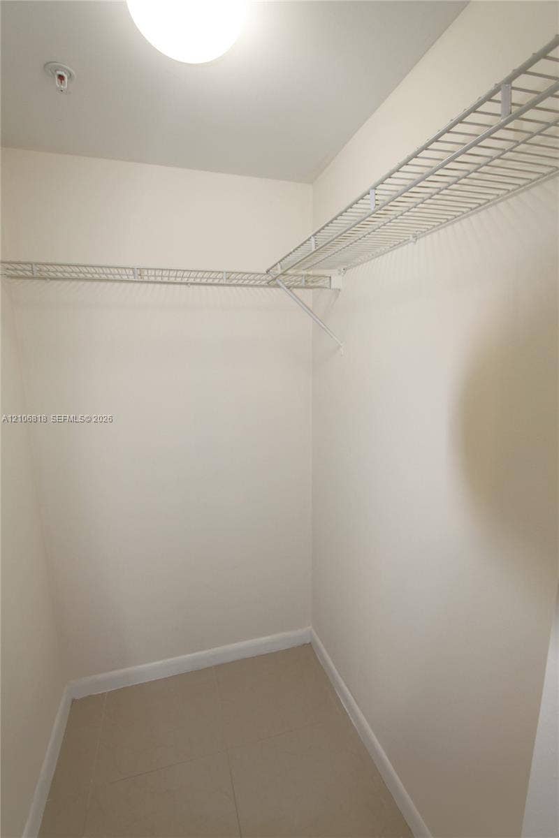 Storage area featuring wall-mounted wire shelving and tile flooring