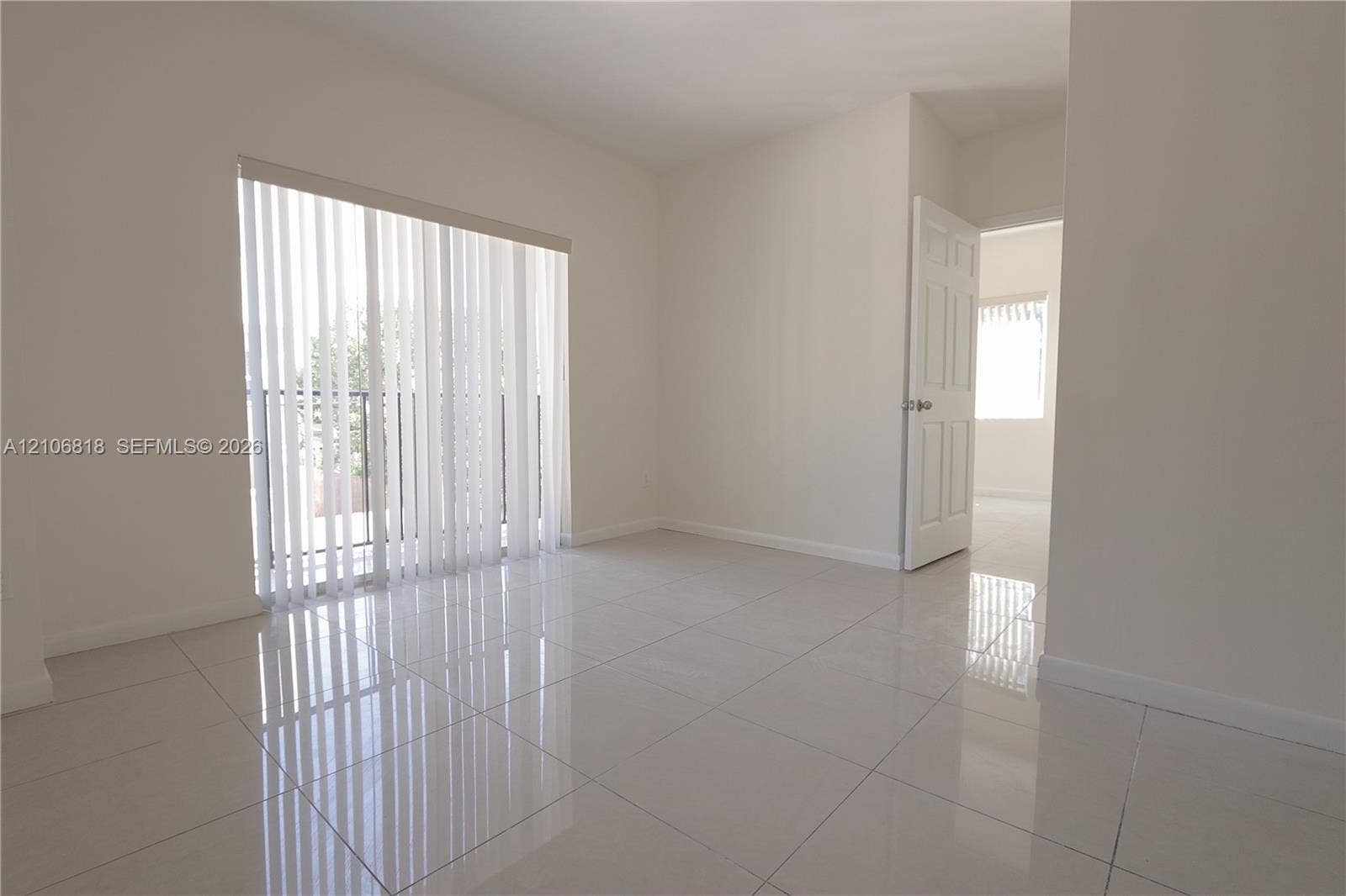 Neutral-toned room featuring large-format ceramic tile flooring, a glass sliding door, and a six-panel interior door