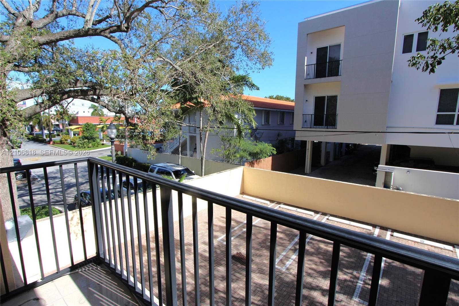 Private balcony featuring black metal railings, tile flooring, and paved parking area