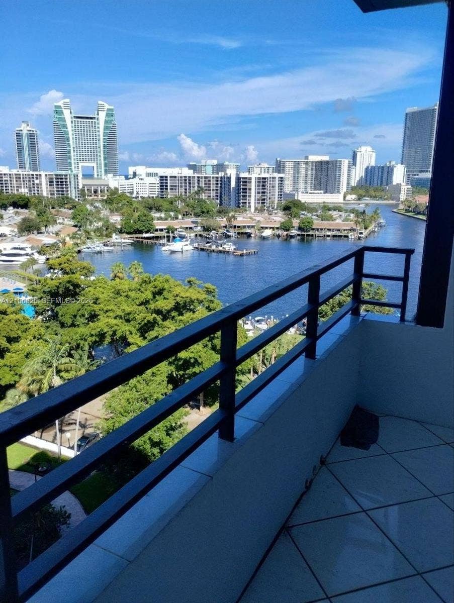 500 Three Islands Boulevard, #822, Hallandale Beach, Hallandale Beach, FL 33009 Private balcony featuring tiled flooring and a metal railing, overlooking a waterway, marina, and urban skyline