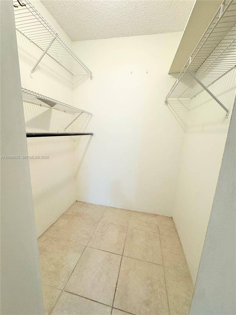 Storage space featuring ceramic tile flooring, multi-level wire shelving, and built-in hanging rods