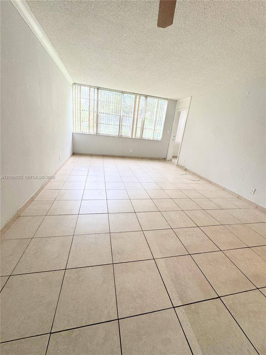 Interior space featuring large-format ceramic tile flooring, neutral walls, and extensive window groupings equipped with vertical blinds