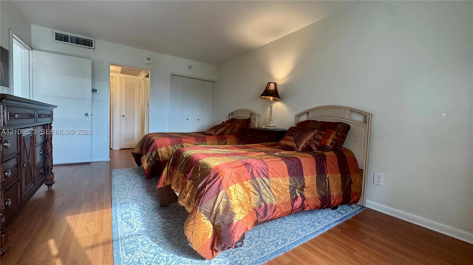 Room featuring wood-finish flooring, dual-panel closet doors, and recessed ceiling integration
