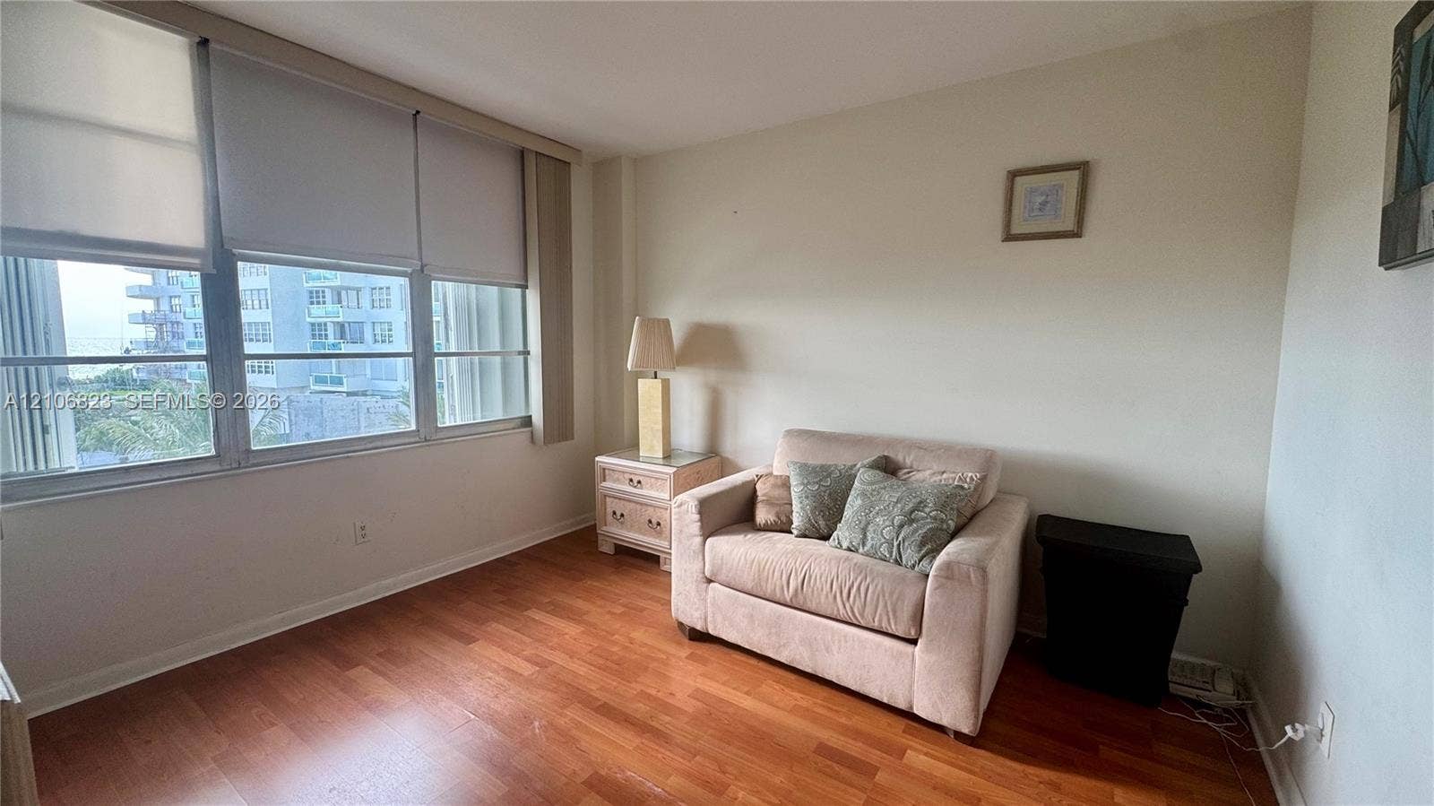 Large windows with integrated roller shades, wood-finish flooring, and neutral wall tones
