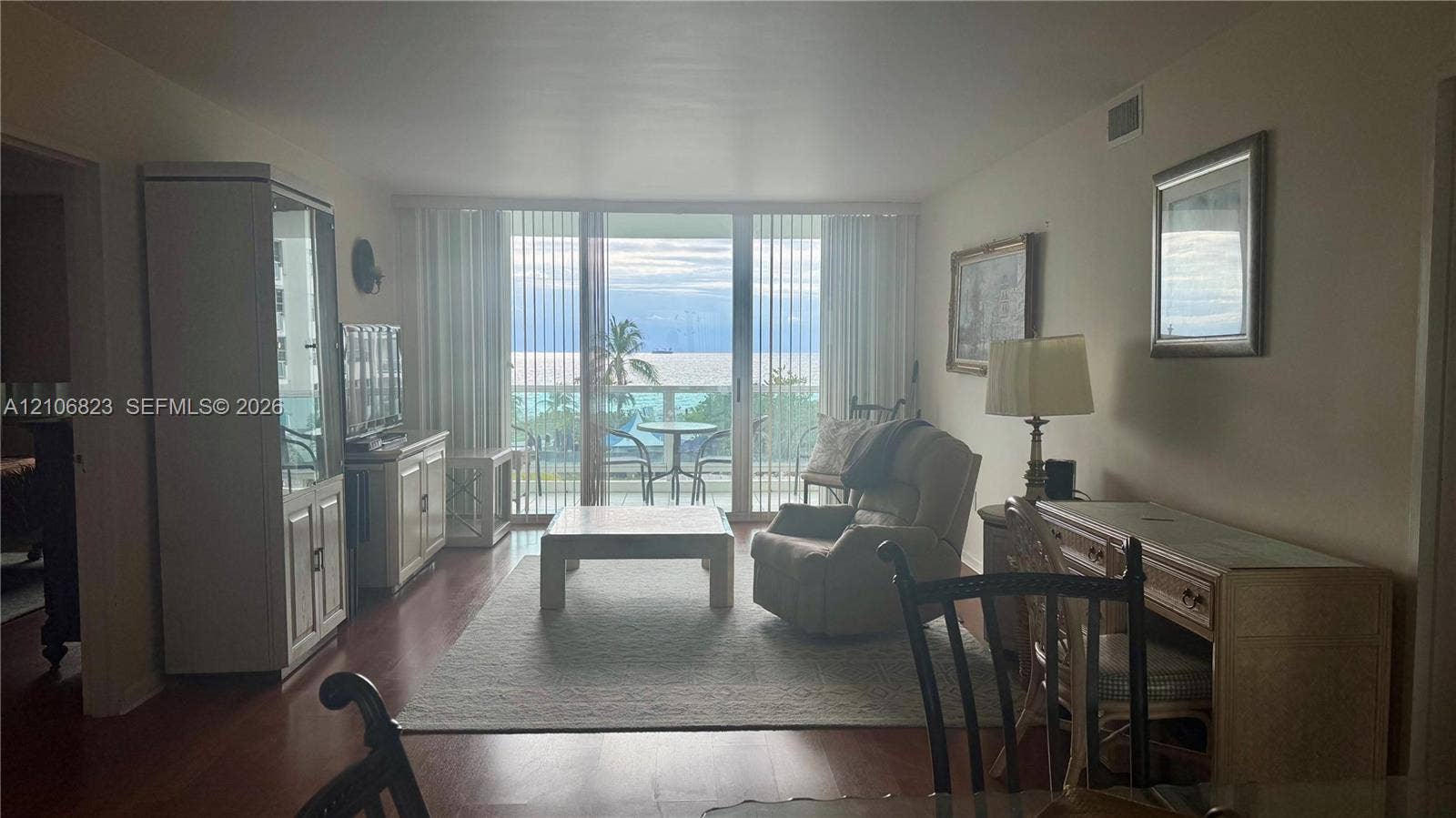 Living area featuring wood-finish flooring, floor-to-ceiling sliding glass doors, and direct access to an exterior balcony