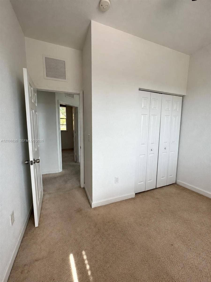 Room featuring neutral carpeting, white interior doors, and a bi-fold closet