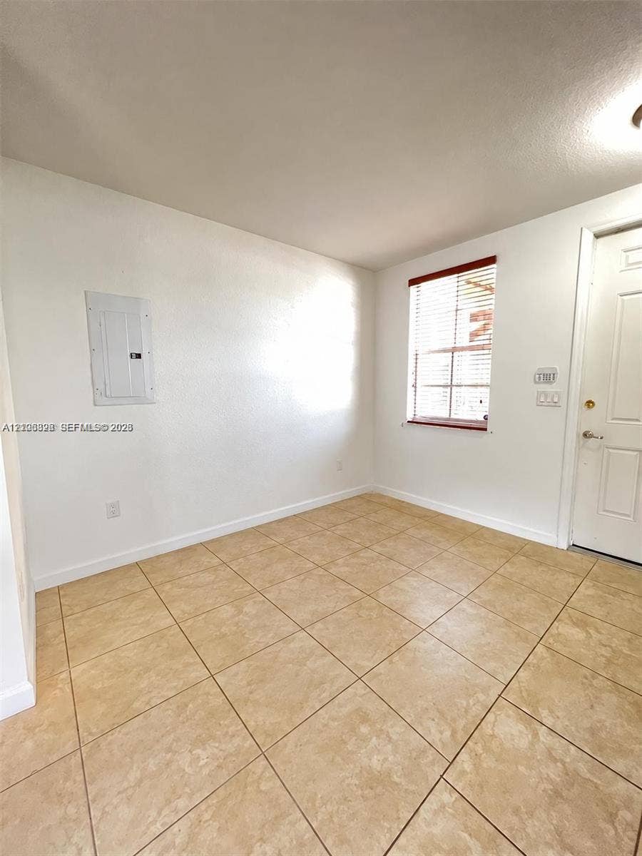 Room featuring neutral wall finishes, tile flooring, a window with horizontal blinds, and a paneled exterior door