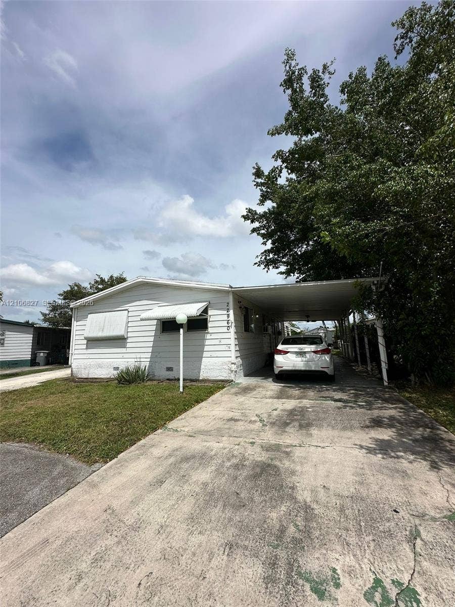 Single-story residence featuring horizontal siding, a covered carport, and metal window awnings